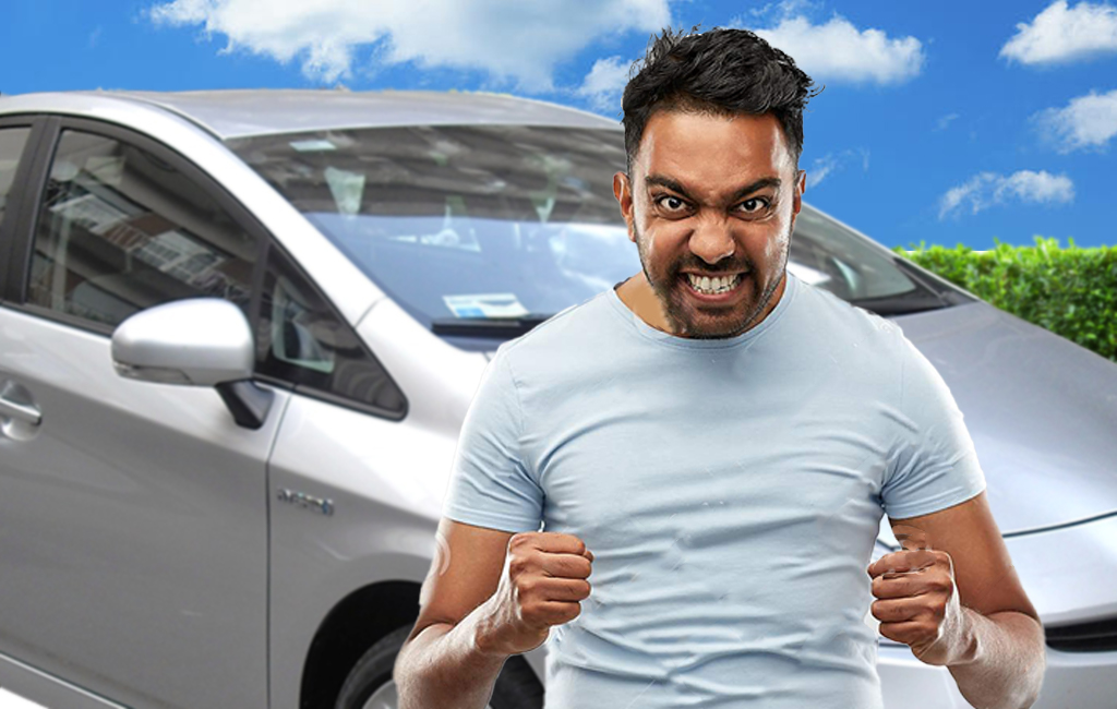 An angry Jay Patel standing next to his silver Toyota Prius.