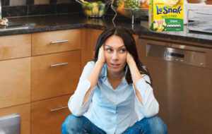 Distressed woman crouching in kitchen