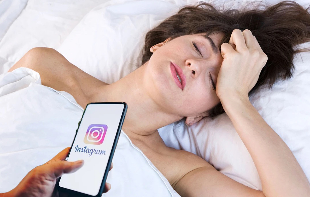 hungover woman in bed looking at instagram