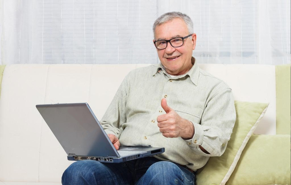 older man with laptop giving thumbs up