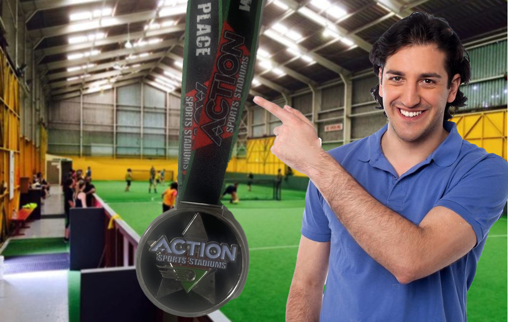 man proudly pointing at indoor sports medal.