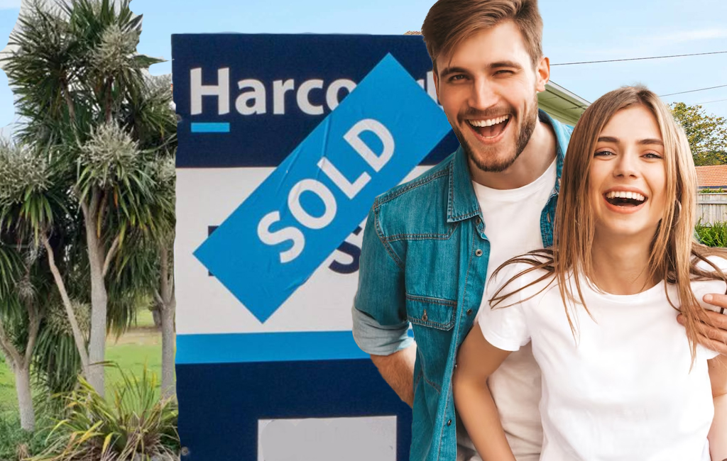 young couple next to sold sign