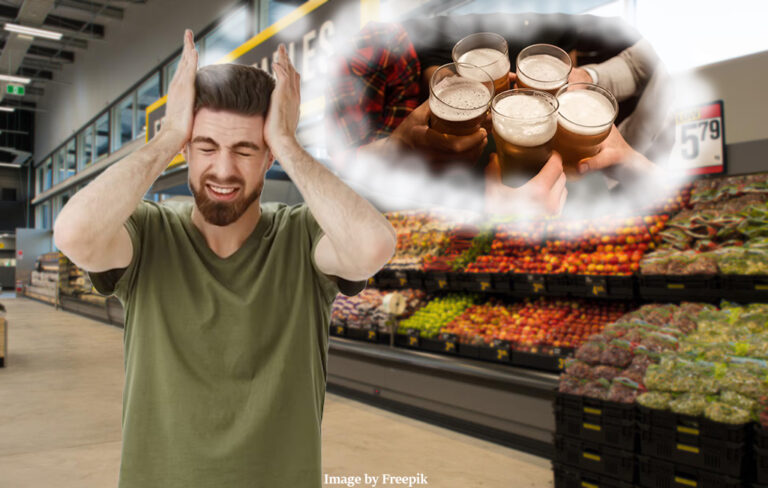 man holding head in supermarket, while thinking of beers.
