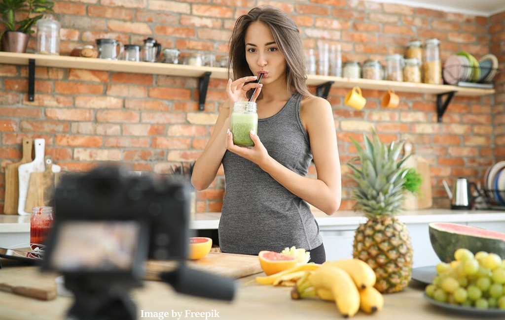 woman drinking smoothie she has just made, with camera pointing at her.
