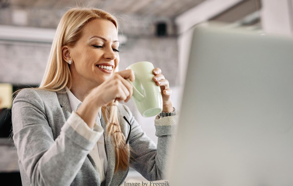 woman drinking coffee at desk.