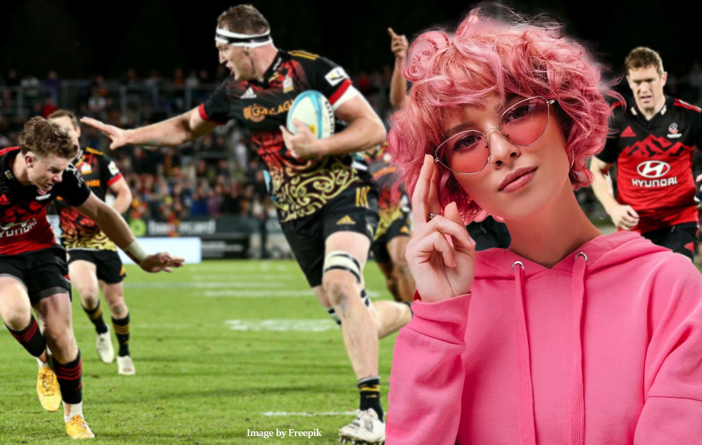 pinke haired woman with chiefs vs crusaders game in background.