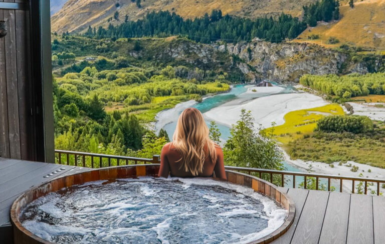 blonde woman in hot pool looking at queenstown