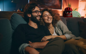 couple relaxing on couch while greedy money-grubbing netflix monster lurks in the background.