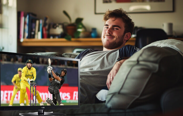 man sitting on couch watching free to air cricket