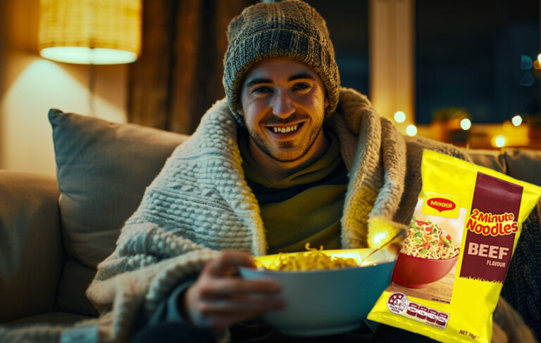 man on couch with winter clothing and two minute noodles packet
