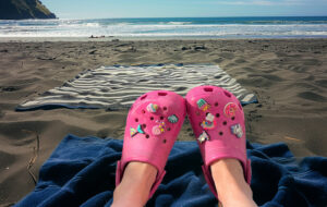 adult wearing pink crocs with jibbitz at the beach