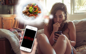 woman on couch looking at netflix on phone, thinking about food.