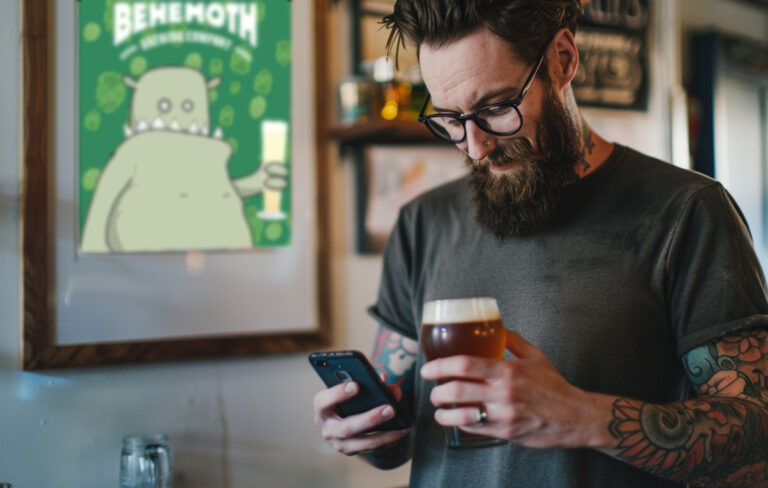 man with beer tweeting on phone at pub