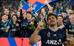 Auckland fc fan with beer and team behind him